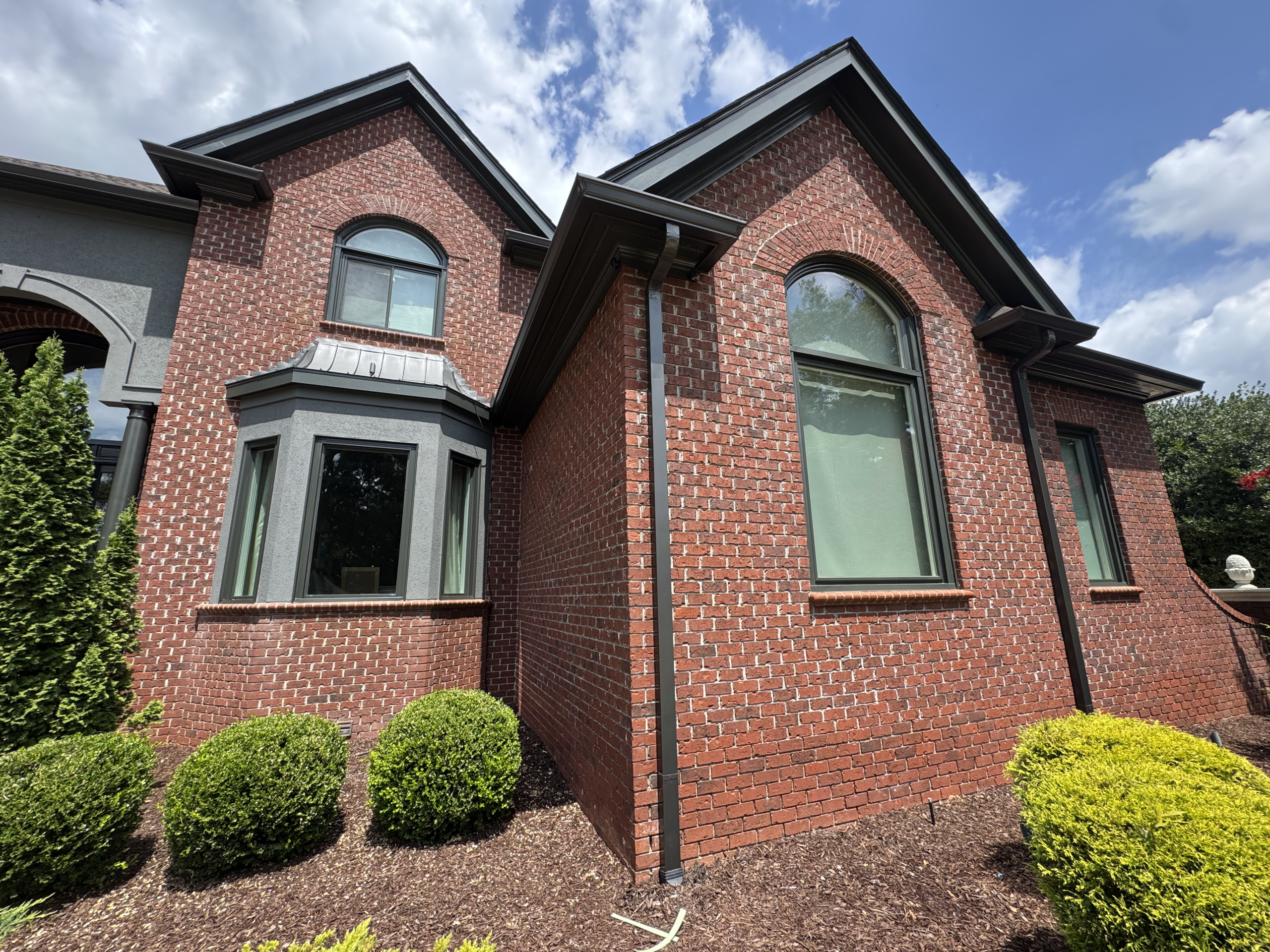 Red brick house with dark trim | GutterCo (About )